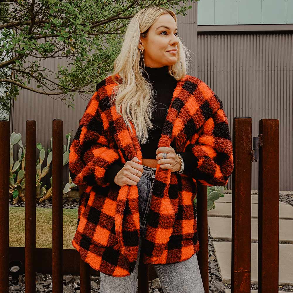  woman wearing a red and black sherpa wrap and jeans