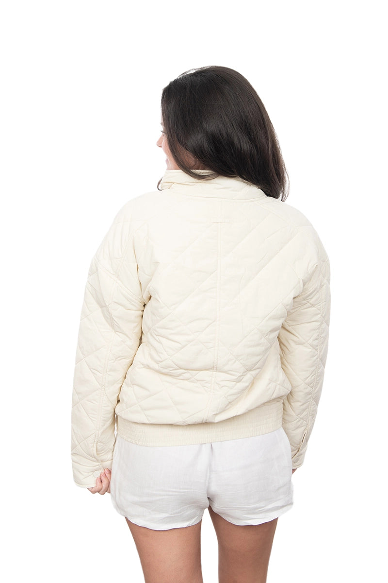 Person wearing a cream-colored puffer jacket and white shorts on a white background