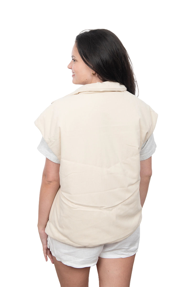 Woman wearing a beige quilted vest on a white background