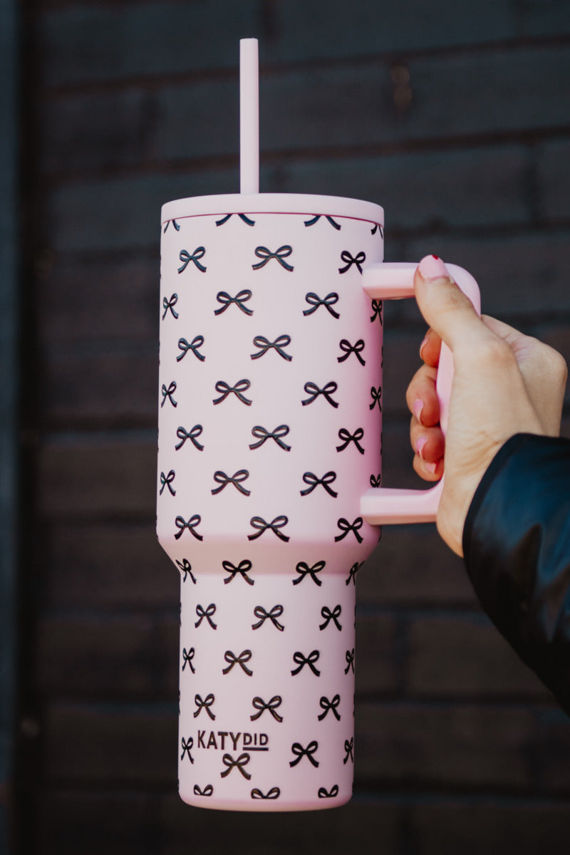A woman holding a pink stainless steel tumbler with pink coquette bows