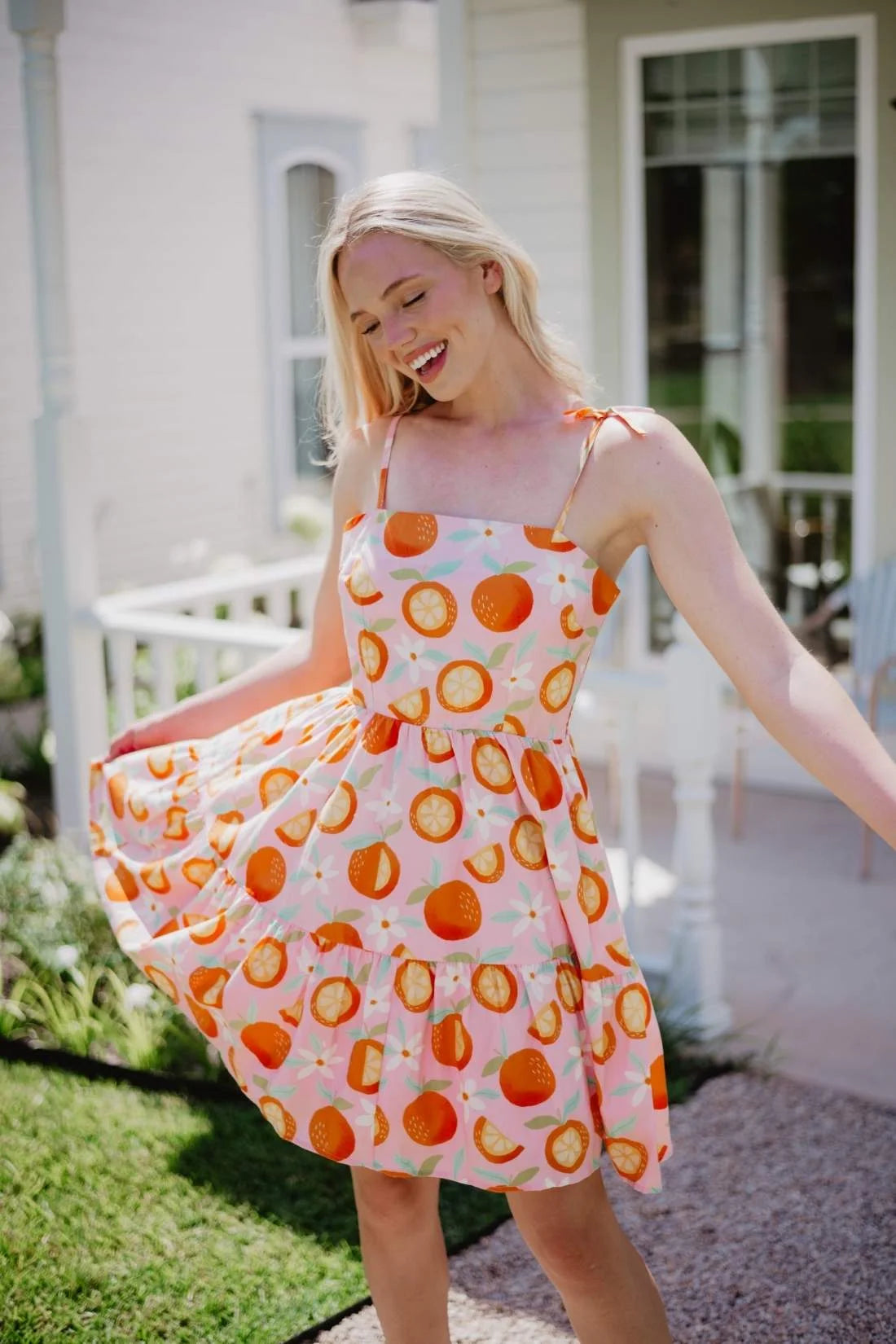 Woman in a oranges dot dress standing outdoors on a sunny day.