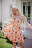 Woman in a oranges dot dress standing outdoors on a sunny day.